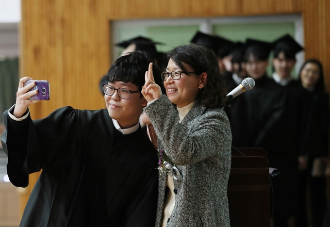 12일 오전 서울 용산구 선린인터넷고등학교에서 열린 제111회 졸업식에서 한 졸업생이 졸업장을 받은 뒤 담임선생님과 셀카를 찍고 있다. 연합뉴스