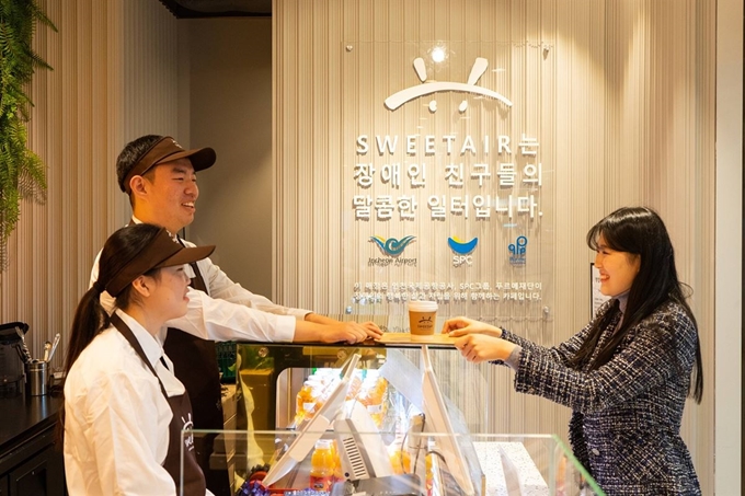 인천국제공항 제2터미널에 위치한 ‘스윗에어 바이 행복한 베이커리&카페’에서 장애인 직원이 고객을 맞이하고 있다. SPC그룹 제공