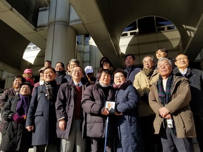 ‘삼형제 간첩조작사건’ 재심 무죄 판결이 나온 지난달 17일 서울 서초동 서울고법 앞에서 최씨 일가족이 환하게 웃으며 기념사진을 찍고 있다. 사형 선고를 받았던 맏형 고 최철교씨의 딸 최종숙씨, 고인의 여동생 최정순씨가 고인의 영정사진을 들고 가운데 섰다. 장경욱 변호사 제공