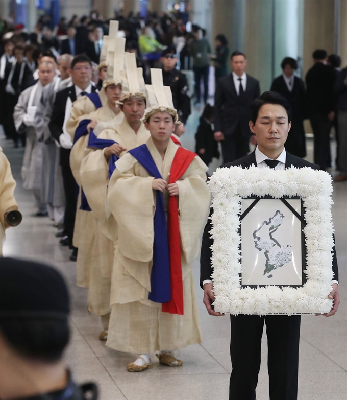 일제 강제징용 희생자 유골 74위가 28일 오후 한반도 그림과 함께 인천국제공항을 통해 봉환되고 있다. 맨 앞에 선 영화배우 박성웅은 봉환 취지를 듣고 자진해 환향식과 노제 등에 참여했다. 뉴스1