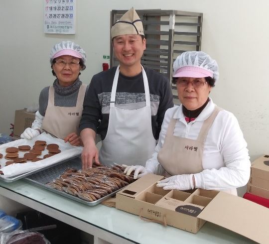 사회적기업 (주)경주제과 이상운 대표가 어르신 직원들과 제빵을 포장하고 있다.