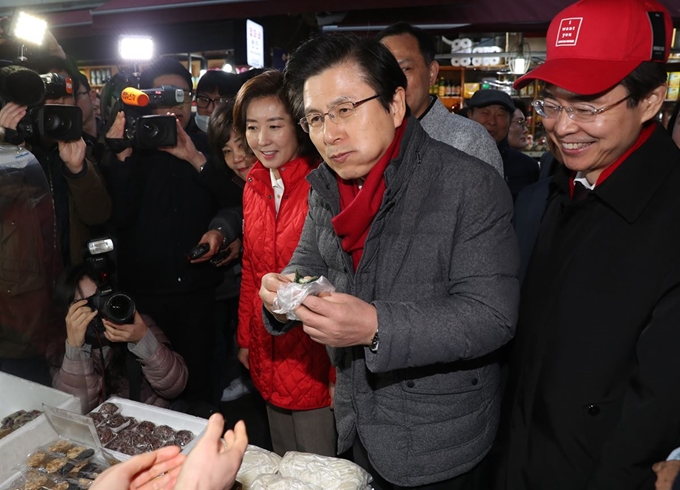 자유한국당 황교안 대표가 5일 새벽 서울 남대문시장을 방문해 시장 상인으로부터 떡을 사서 맛보고 있다. 연합뉴스