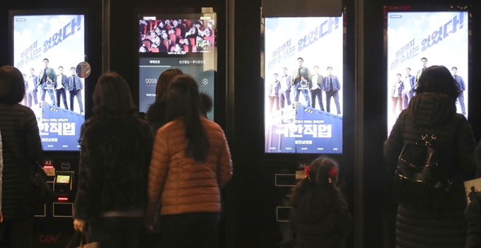 영화 '극한직업'이 1,000만 관객 돌파를 앞둔 6일 서울 영등포 한 영화관에서 관객들이 '극한직업' 포스터를 보고 있다. 일각에서 '극한직업'이 설 연휴 기간 스크린을 지나치게 많이 차지한다는 비판이 제기됐다. 연합뉴스