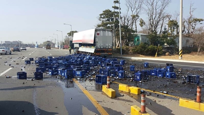 8일 오전 경남 사천시 축동면 남해고속도로 사천나들목 인근 교차로에서 25t 화물차 적재함에 실려있던 맥주 70박스가 우회전 중 도로에 쏟아져 경찰이 주변을 통제하고 있다. 경찰 제공=연합뉴스