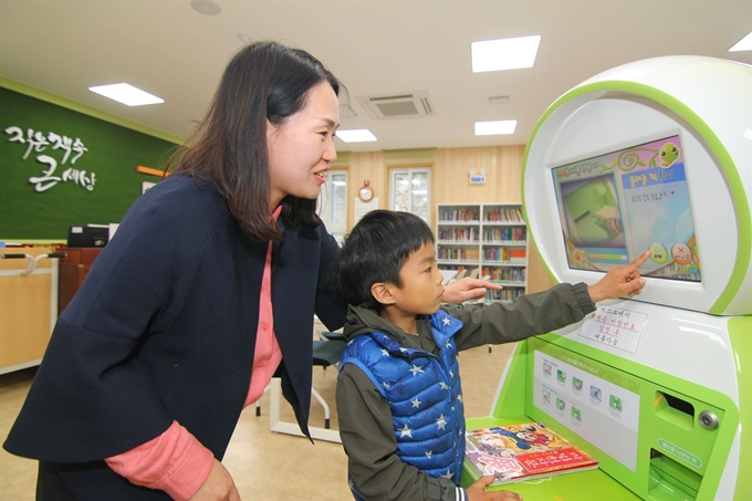 한 초등학생이 13일 대구 달서구 두류도서관에서 직원의 도움을 받아 자동대출반납기를 통해 빌린 책을 반납하고 있다. 두류도서관은 지난해 7월부터 노후 시설을 리모델링한 후 이날 재개관식을 가졌다. 김민규기자 whitekmg@hankookilbo.com