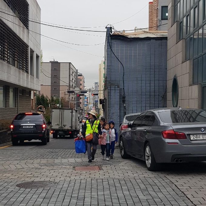 수원시는 초등학교 저학년 아이들의 안전 등하교를 위해 안전지도사업을 펴고 있는 가운데 한 안전지도사가 아이들과 함께 걸어가고 있다. 수원시 제공