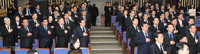 자유한국당 의원들이 15일 국회에서 열린 의원총회에 '의회 민주주의 사망'을 주장하며 검정색 옷과 넥타이를 착용하고 참석해 국민의례를 하고 있다. 오대근기자