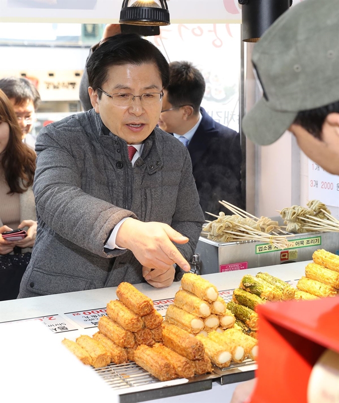 자유한국당 황교안 대표가 19일 오전 민생탐방 '국민과 함께'를 위해 찾은 서울 마포구 서교동 홍익대학교 삼거리에서 지역 상인으로부터 경기현황을 전해 듣고 음식을 직접 사서 먹고 있다. 연합뉴스