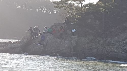 23일 오후 충남 태안군 솔섬 인근 해상 갯바위에 고립된 해루질 동호회원 11명이 해경의 구조를 기다리고 있다. 태안 해경 제공.