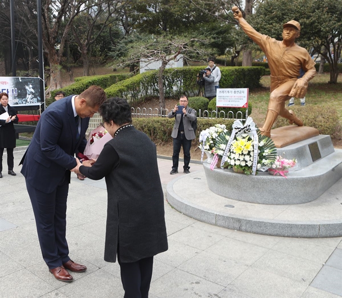 25일 부산 사직야구장 마당에 있는 고 최동원 선수 동상에서 이대호 프로야구선수협의회 회장이 헌화한 뒤 최 선수의 모친인 김정자 여사에게 꽃바구니를 건네고 있다. 연합뉴스