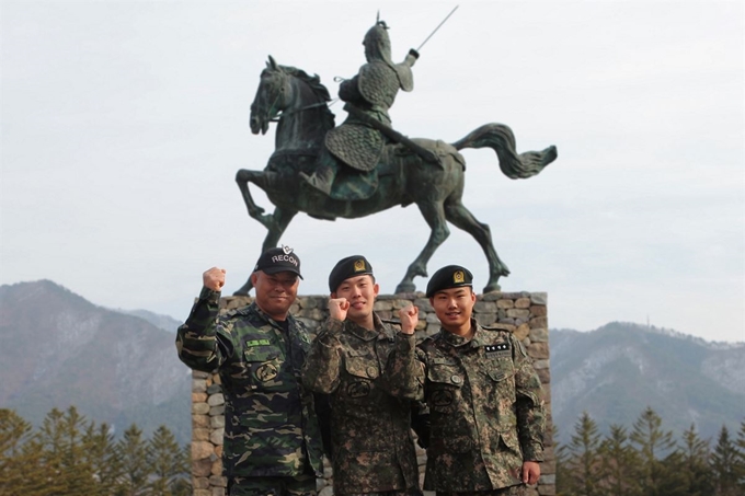 아버지 남병락(왼쪽)씨의 뒤를 이어 동부전선 육군 12사단 수색대대 2중대서 근무하는 남대효(가운데) 상병과 남효택 일병이 부대 내 을지문덕상 앞에서 파이팅 포즈를 취하고 있다. 육군 제공