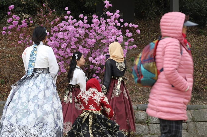 꽃샘추위가 찾아온 31일 서울 창덕궁에서 관광객들이 기념촬영을 하고 있다. 그 옆을 쌀쌀한 날씨에 두툼한 외투를 입은 시민이 걸어가고 있다. 연합뉴스