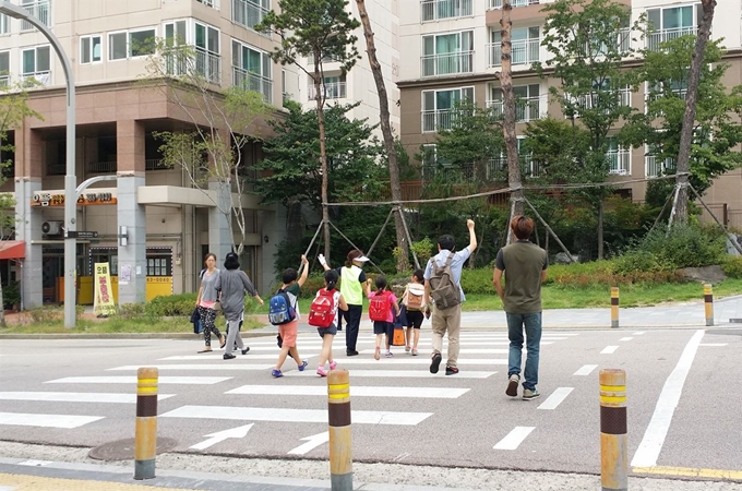 어린이보호구역에서 교통안전지도사들이 어린이와 함께 횡단보도를 건너고 있다. 서울시 제공