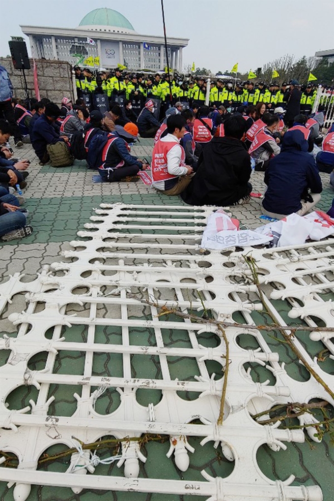 3일 오전 민주노총 조합원들이 노동법 개악 저지 등을 촉구하며 국회 경내 진입을 시도하다 뜯겨진 철문 앞에서 농성을 이어가고 있다. 연합뉴스