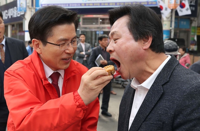 자유한국당 황교안 대표가 8일 오후 경남 창원시 성산구 반송시장을 찾아 시민 인사 중 강기윤 당시 4·3 보궐선거 후보(오른쪽)에게 풀빵을 건네고 있다. 연합뉴스