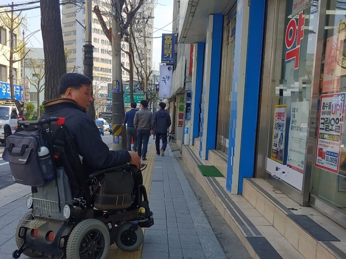 11일 서울 중구 한 약국 입구에서 2급 지체장애인인 주정수(64) 한국방송통신대 법률봉사단장이 턱 때문에 들어가지 못하고 있다. 정준기 기자