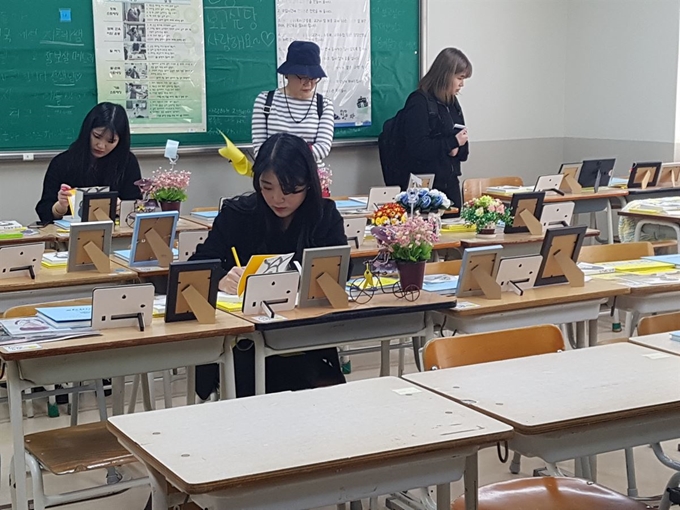 16일 오전 경기 안산교육지원청에 있는 4ㆍ16 기억교실을 찾은 시민들이 희생 학생 책상 위에 놓인 노트에 추모글을 남기고 있다. 임명수 기자