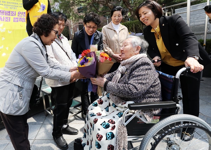 17일 서울 종로구 옛 일본대사관 앞에서 열린 일본군성노예제 문제해결을 위한 1383차 정기 수요시위에서 길원옥 할머니가 햇살사회복지회 할머니들에게 꽃다발을 전달하고 있다. 뉴스1