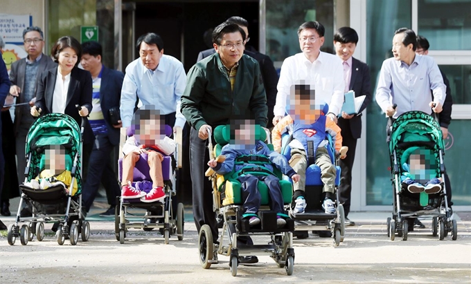 황교안 자유한국당 대표(가운데)가 19일 오후 인천시 연수구 동춘동 장애인 영·유아 시설 동심원을 방문해 장애우들과 산책하고 있다. 연합뉴스