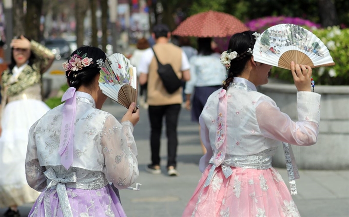 전주 낮 최고기온이 28도까지 오르는 등 초여름 날씨를 보인 22일 오후 전북 전주시 한옥마을에서 관광객들이 부채와 양산, 손으로 햇볕을 가리며 거리를 걷고 있다. 뉴스1