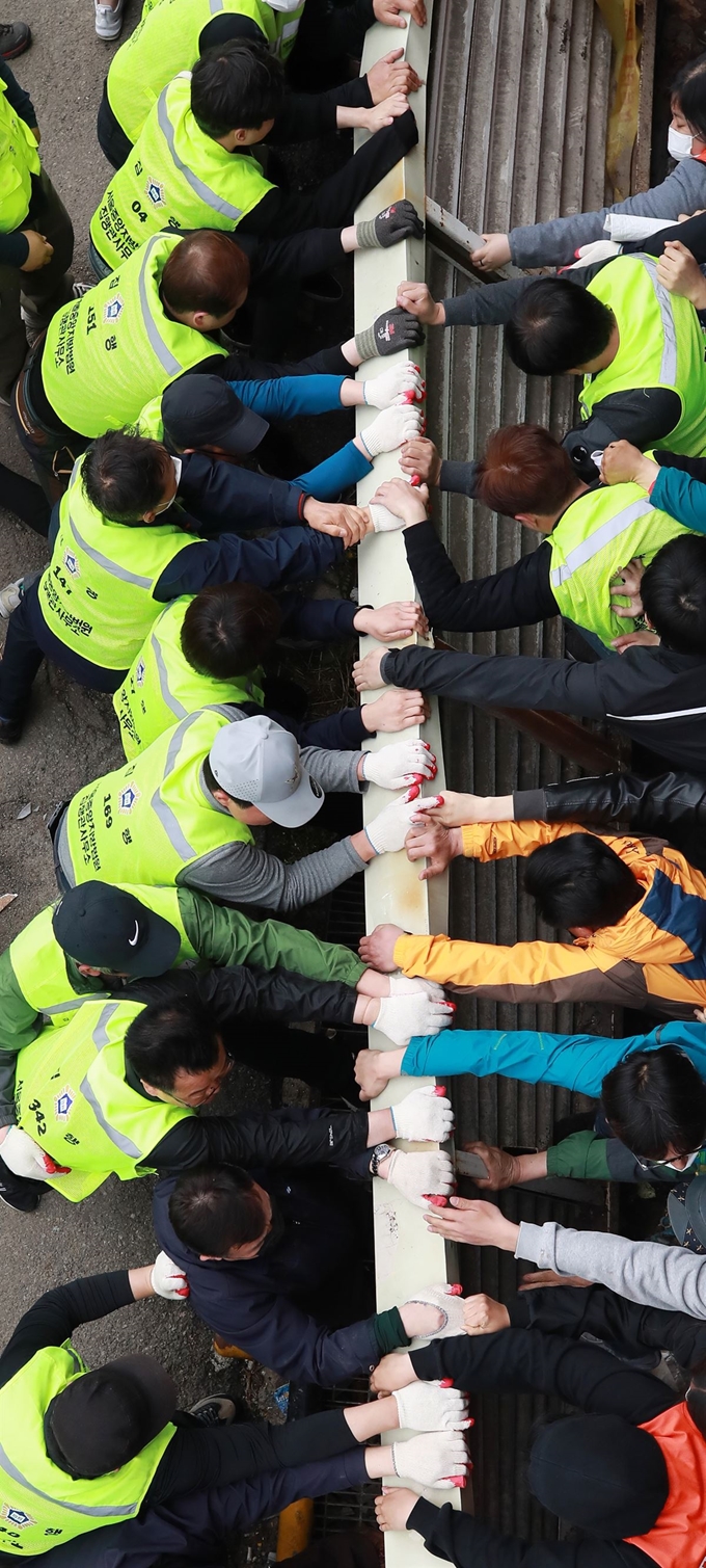 25일 구 노량진수산시장 주차 타워에서 집행인력들이 걷어내려는 철제 울타리를 상인과 시민사회단체 회원들이 붙잡고 있다. 연합뉴스