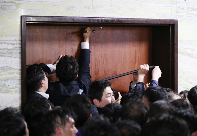 공수처 법안을 제출을 막기 위해 자유한국당 당직자들이 국회 의안과를 안에서 봉쇄하자 국회 사무처가 '도구'를 이용해 출입문을 열려고 시도하고 있다. 연합뉴스