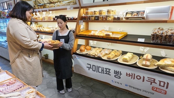 구미 대표 빵 '베이쿠미' 지정판매업소 중 하나인 구미 원평동 카페 쿠미를 방문한 손님들이 베이쿠미 빵을 들어보이고 있다. 베이쿠미는 출시 2주년을 맞아 다음달 1~10일 10% 할인 행사를 진행한다. 김재현기자 k-jeahyun@hankookilbo.com