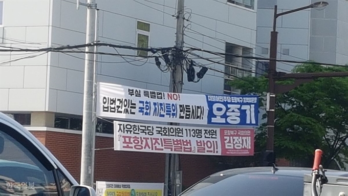 경북 포항시내 한 교차로에 자유한국당 김정재 국회의원과 더불어민주당 오중기 포항북구지역위원장 이름이 크게 적힌 현수막이 걸려 있다. 김정혜기자 kjh@hankookilbo.com