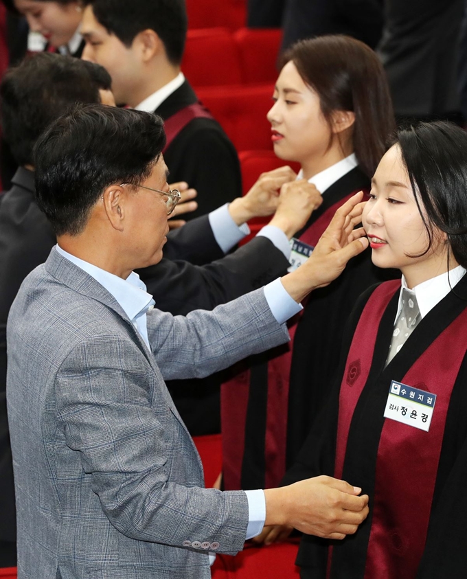 8일 오후 경기도 과천시 정부과천청사 지하 대강당에서 열린 신임 검사 임관식에서 가족들이 신임 검사에게 법복을 입혀준 후 얼굴을 어루만지고 있다. 뉴스1