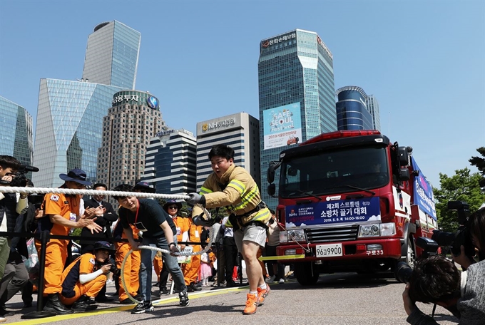 9일 서울 영등포구 여의도공원에서 열린 2019 서울안전한마당 '스트롱맨 소방차 끌기 대회'에서 소방관이 맨몸으로 11톤 소방차를 끌고 있다. 미세먼지와 화재&middot;교통&middot;생활&middot;환경 등 다양한 안전문화체험 프로그램으로 꾸며진 제13회 서울안전한마당은 오는 11일까지 사흘간 여의도공원 문화의 마당에서 펼쳐진다. 뉴스1