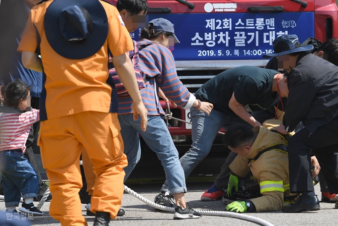 9일 서울 여의도공원에서 열린 ‘제2회 소방차 끌기 대회’에 참가한 한 소방관이 시작과 동시에 땅바닥에 쓰러지자 가족들과 관계자들이 놀라서 부축하고 있다. 서재훈 기자