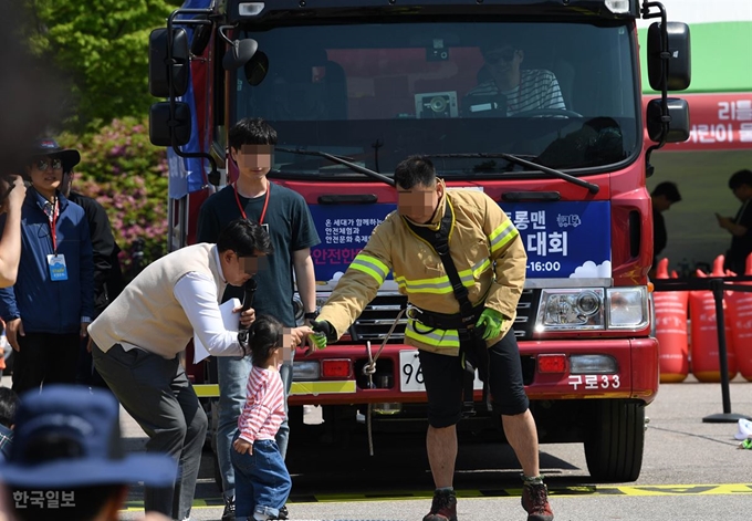 9일 서울 여의도공원에서 열린 제2회 소방차 끌기 대회에 참가한 소방관이 경기 시작 전 딸과 손 인사를 하고 있다. 서재훈 기자