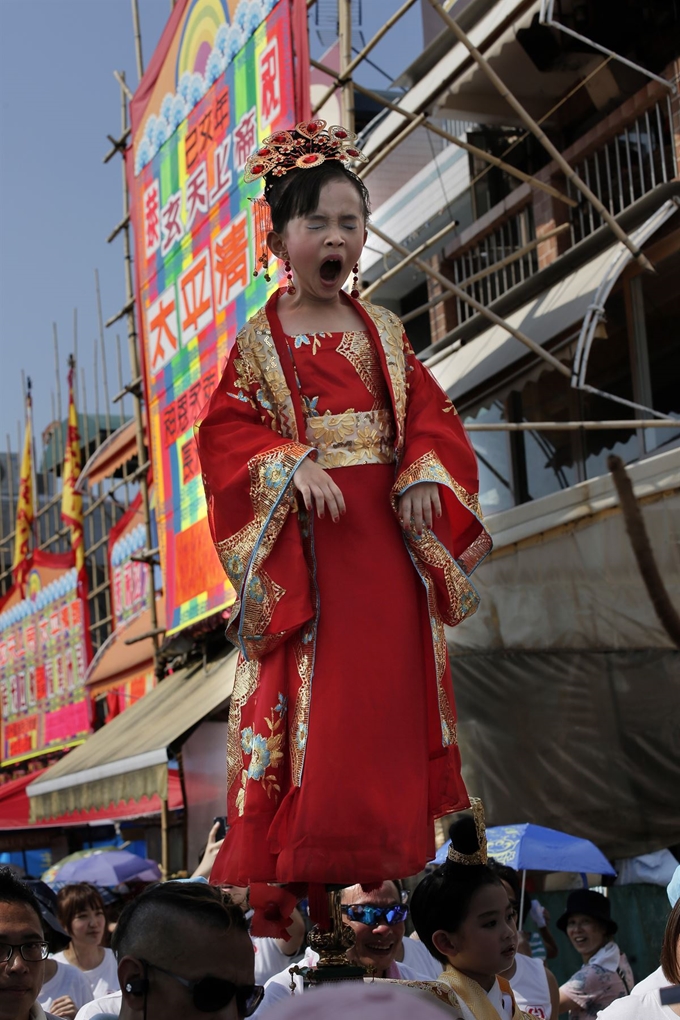 12일(현지시간) 홍콩 청차우에서 연례 축제 ‘빵 축제(Bun Festival)’가 열려 숨겨진 금속 지지대로 몸을 지탱한 한 어린이가 공중에 떠 퍼레이드를 하고 있다. 해마다 5월 초에 열리는 이 축제에는 수천 명이 축제를 보기 위해 몰려들었고 어린이들은 전통의상 등을 입고 공중에 떠 퍼레이드를 펼쳤다. AP=연합뉴스