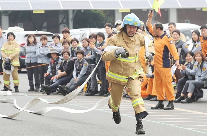 14일 제주시 한라체육관에서 열린 ‘의용소방대 소방기술경연대회’ 소방호수끌기 대회에서 의용소방대원이 소방호수를 들고 뛰어가고 있다. 뉴스1