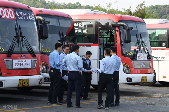 Figure 2 [저작권 한국일보].15일 전국에서 시내버스 파업이 예고된 가운데 14일 경기 용인시 경남여객 차고지에서 기사들이 버스 앞에서 파업관련 대화를 나루고 있다. 배우한 기자