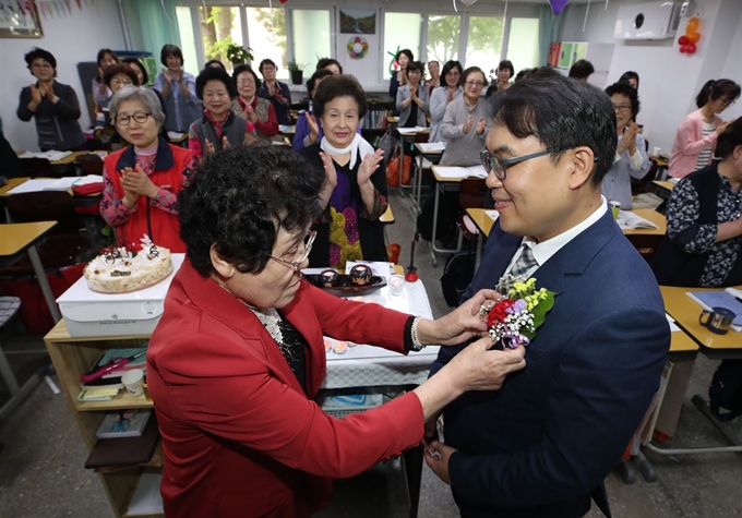 스승의 날인 15일 서울 마포구 일성여자중고등학교에서 만학도 할머니가 선생님에게 카네이션을 달아주고 있다. 연합뉴스