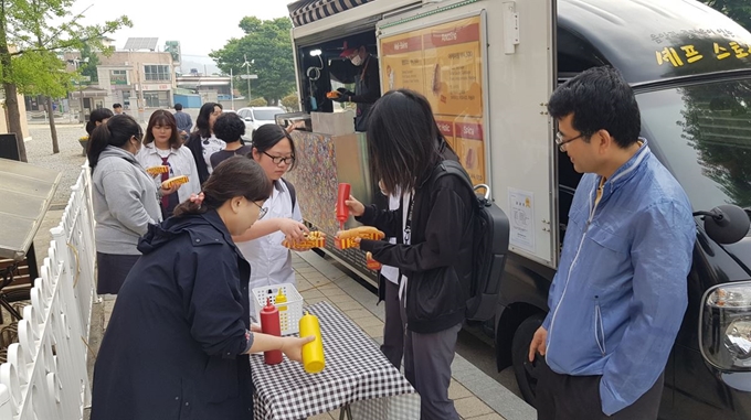 증평공고 교사들이 15일 푸드트럭에서 핫도그를 만들어 등교하는 학생들에게 나눠주고 있다. 증평공고 제공