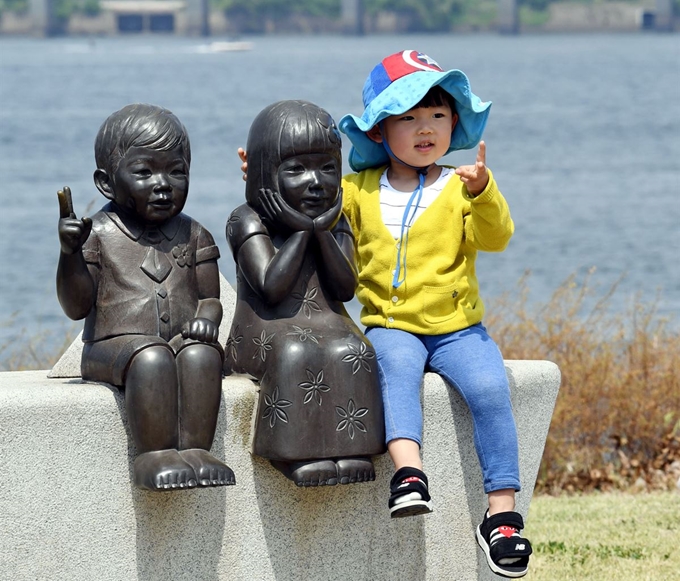 한 아이가 여의도 한강시민공원에 설치된 동상에 다가가 친밀감을 표현하고 있다.