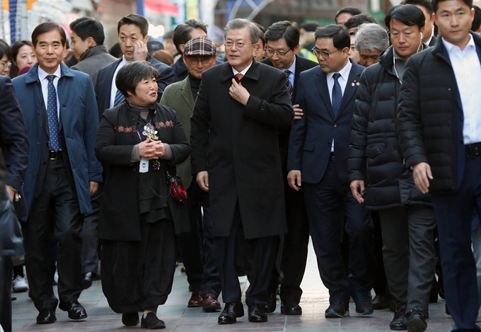 문재인 대통령이 지난해 12월 경남 창원시 창동예술촌에서 김경년 문화관광해설사(왼쪽 두 번째)의 설명을 들으며 걷고 있다. 청와대사진기자단