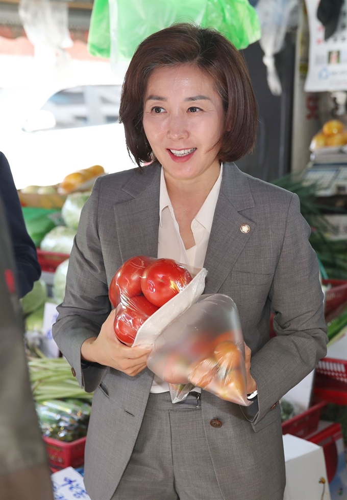 자유한국당 나경원 원내대표가 22일 서울 관악구 신림동 일대에서 소상공인특위·소폐경활특위 소상공인 현장간담회에 앞서 지역 상인들의 애로사항을 듣고 과일을 구매하고 있다. 연합뉴스