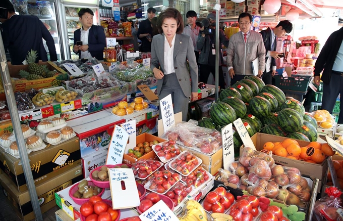 자유한국당 나경원 원내대표가 22일 서울 관악구 신림동 일대에서 소상공인특위·소폐경활특위 소상공인 현장간담회에 앞서 지역 상인들의 애로사항을 듣고 과일을 고르고 있다. 연합뉴스