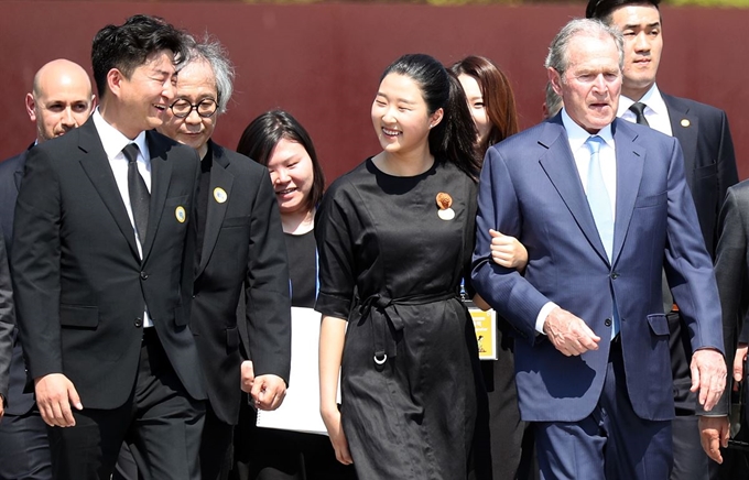 23일 오후 경남 김해시 진영읍 봉하마을에서 열린 노무현 대통령 서거 10주기 추도식에서 참배를 마친 부시 전 미국 대통령이 노 전 대통령 손녀이자 아들 건호 씨 딸과 팔짱을 끼고 이동하고 있다. 맨 왼쪽은 노 전 대통령 아들 건호 씨. 연합뉴스