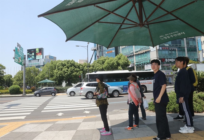 제주지역 낮 최고기온이 30도를 넘어선 23일 제주시 노형로타리 횡단보도에서 도민들이 뜨거운 햇빛을 피해 그늘막 아래로 들어가 신호를 기다리고 있다. 제주=연합뉴스