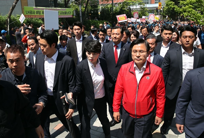 자유한국당 황교안 대표가 24일 오전 경기도 수원 영통구 광교센트럴타운 60단지 주민지원센터에서 수도권 부동산 대책 점검을 위해 간담회장으로 향하고 있다. 뒤는 황 대표의 방문을 환영하는 지지자들과 방문을 반대하는 민주노총과 민중당 관계자들이 든 손팻말 모습. 연합뉴스