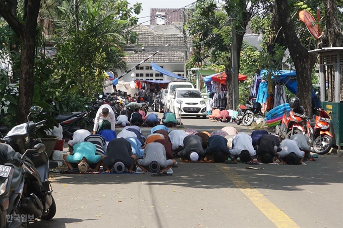 라마단 기간인 24일 미처 사원에 도착하지 못한 상태에서 금요일 연합예배가 시작되자 무슬림들이 즉석에서 차가 다니는 도로에 자리를 깔고 기도하고 있다. 자카르타=고찬유 특파원