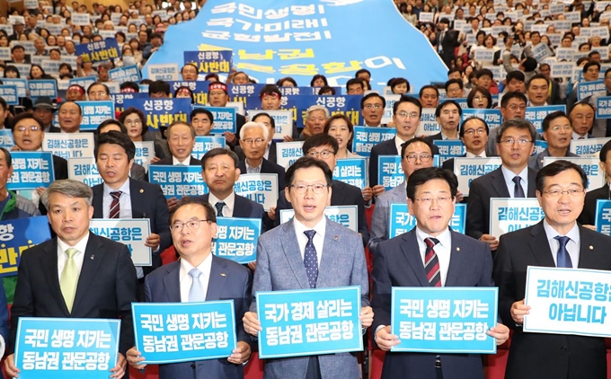 5월 27일 오후 국회 의원회관에서 열린 '부·울·경 동남권 관문공항 검증결과 대국민 보고회'에 부산ㆍ울산ㆍ경남에 지역구를 둔 더불어민주당 국회의원들과 김경수(앞줄 가운데) 경남지사, 오거돈(앞줄 왼쪽 두 번째) 부산시장 등이 참석해 구호를 외치고 있다. 연합뉴스