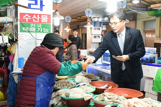 장충남(오른쪽) 남해군수가 지역화폐 ‘화전’ 사용을 권장하기 위해 재래시장을 찾아 직접 화전으로 장을 보고 있다. 남해군 제공