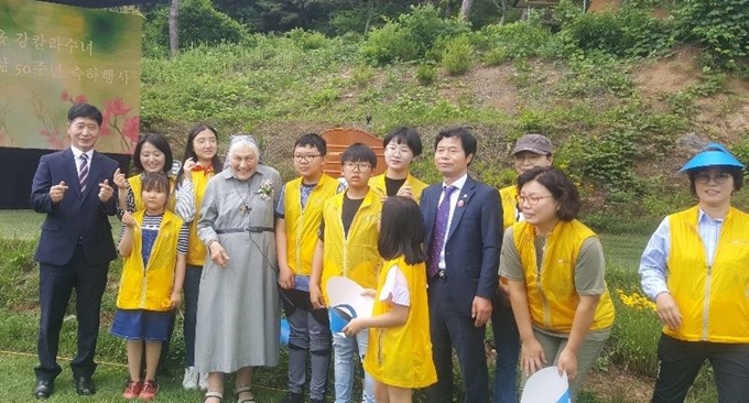 강칼라 수녀가 자원봉사자와 기념촬영을 하며 활짝 웃고 있다.