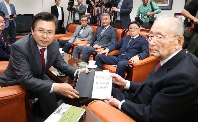 황교안(왼쪽) 자유한국당 대표가 10일 오후 서울 용산 전쟁기념관 군사 편찬연구 자문위원장실에서 6·25전쟁 영웅으로 불리는 백선엽 장군(예비역 대장)을 예방, 백 장군의 저서 '징비록'을 선물 받고 있다. 연합뉴스