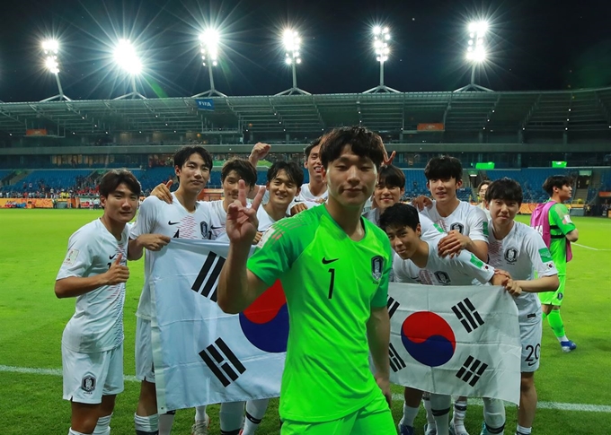 11일 오후(현지시간) 폴란드 루블린 경기장에서 열린 2019 국제축구연맹(FIFA) 20세 이하(U-20) 월드컵 4강전 한국과 에콰도르의 경기가 1-0 한국의 승리로 끝난 뒤 U-20 대표팀 선수들이 태극기를 들고 기념사진을 찍을 때 이광연 골키퍼가 앞을 지나며 손가락으로 V자를 그리고 있다. 연합뉴스